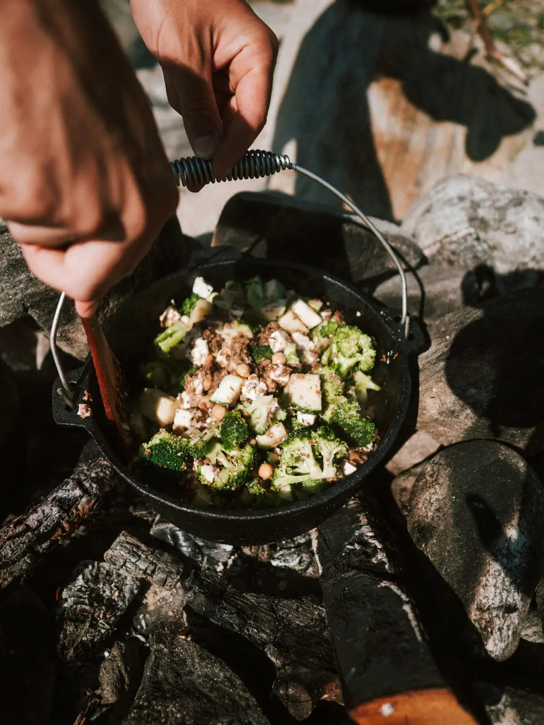Vegetables and tofu cooking in a cast-iron Dutch oven over a campfire
